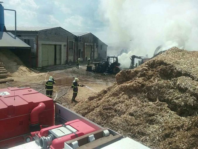 Foto: Oheň zachvátil traktor a rozšíril sa na kopu pilín a štiepky, požiar likvidujú desiatky hasičov